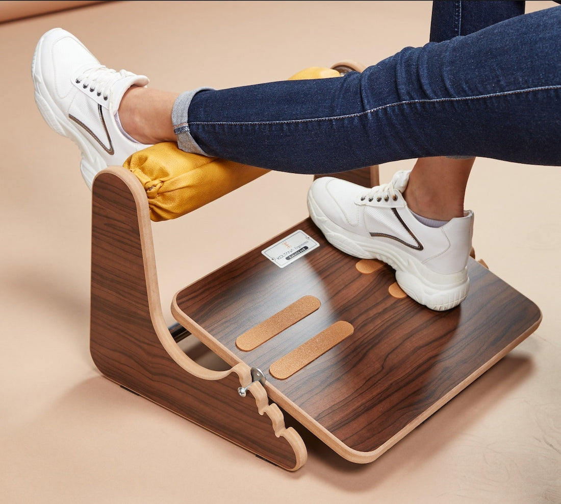 Person using a wooden footrest on a beige surface